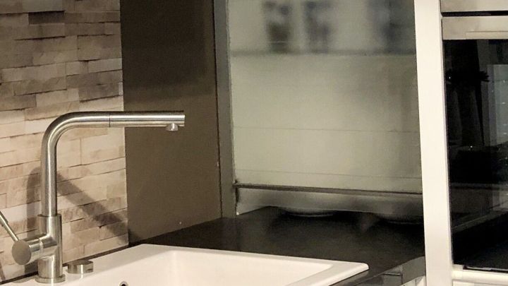 Eine Emaille-Sp&uuml;le steht auf einem dunklen Arbeitsbereich, w&auml;hrend im Hintergrund eine moderne K&uuml;cheneinrichtung sichtbar ist.