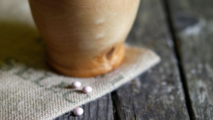 Ein M&ouml;rser steht auf einem Holzofen, w&auml;hrend ein St&ouml;&szlig;el darin ruht, um Medikamente f&uuml;r Katzen oder Kater vorzubereiten.