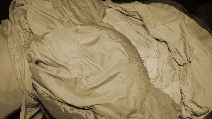 Ein leicht gefalteter, beiger Schlafsack liegt auf einem Tisch und ist bereit f&uuml;r den Einsatz in der Natur oder beim Camping.