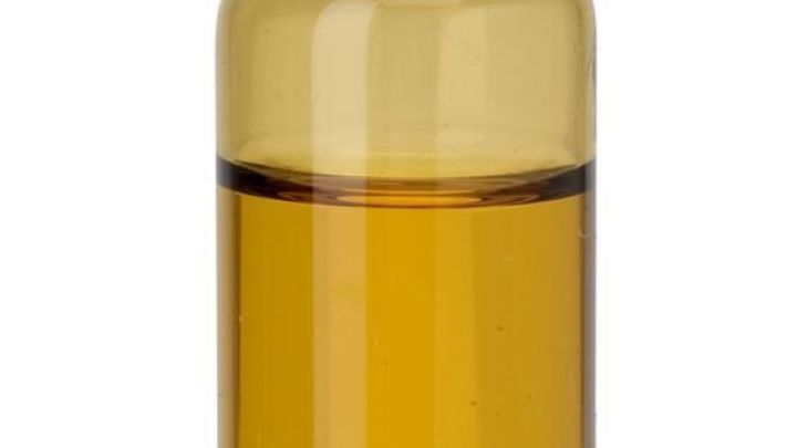 Eine braune Glasflasche mit Teebaum&ouml;l steht vor wei&szlig;em Hintergrund.