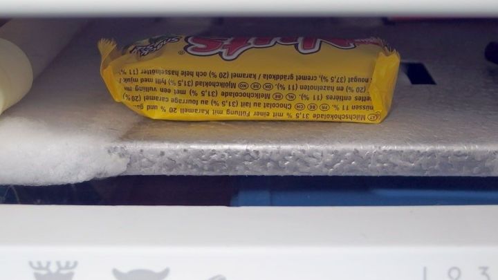 Ein Schokoriegel liegt auf einem Regal im Gefrierfach und wartet darauf, gefroren zu werden.
