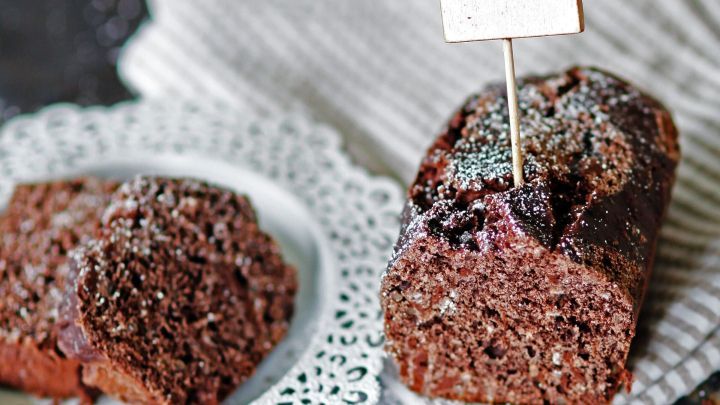 Saftiger Bananen-Schoko-Kuchen auf einem Teller, dekoriert mit einem Schild "LIEBE gemacht", umgeben von einem hellen Tuch.