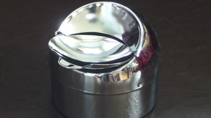 Ein gl&auml;nzender Aschenbecher aus Metall steht auf einer dunklen Oberfl&auml;che, bereit zum Einsatz f&uuml;r saubere Rauchergewohnheiten.