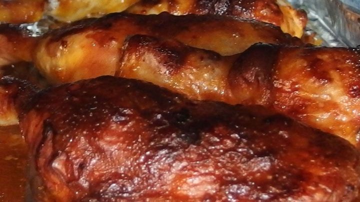 Knusprige Haut um gegrilltes H&auml;hnchen, das appetitlich angerichtet auf einem Backblech liegt, umgeben von gl&auml;nzender Marinade.