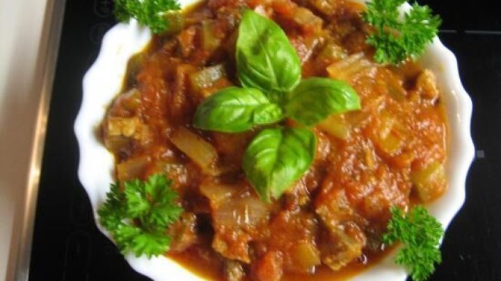 Ein gegrilltes Nackensteak wird in einer Sch&uuml;ssel mit einer Tomatenso&szlig;e und frischen Kr&auml;utern serviert.