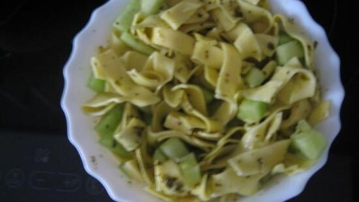 Ein bunter Nudelsalat mit Honigmelone und K&auml;se ist in einer wei&szlig;en Sch&uuml;ssel angerichtet und auf einer Kochplatte platziert.