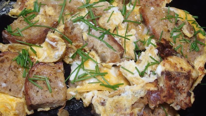 Eierspeise mit R&ouml;sti und frischem Schnittlauch liegt in einer schwarzen Pfanne, bereit zum Servieren und Genie&szlig;en.