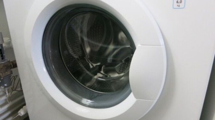 Eine moderne Waschmaschine mit einer runden T&uuml;r, die sich &ouml;ffnet. Sie ist bereit, das Maschinen-Waschprogramm zu nutzen.