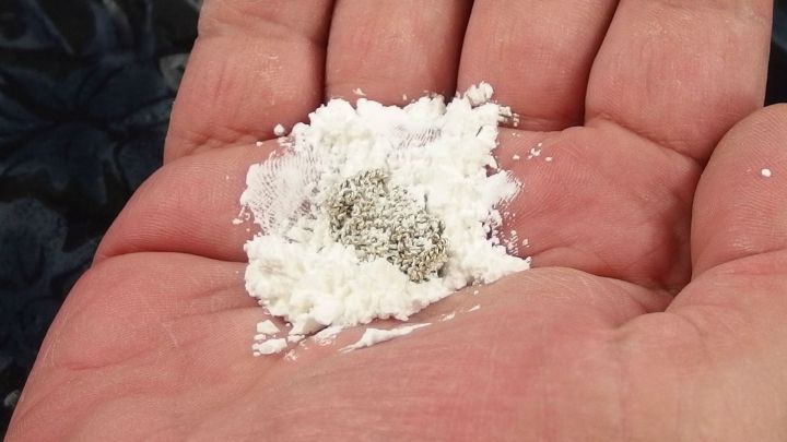 Eine Hand h&auml;lt ein B&uuml;ndel verhedderter Ketten, umgeben von wei&szlig;er Speisest&auml;rke als Unterst&uuml;tzung zum Entwirren.