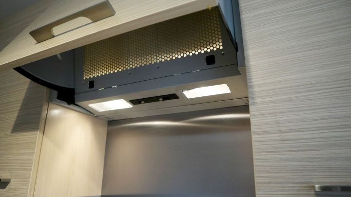 Dunstabzugshaube im K&uuml;chenschrank, offen, enth&uuml;llt sauber gl&auml;nzendes Filter- und Beleuchtungssystem.