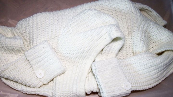 Wei&szlig;es Strickkleid liegt ordentlich gefaltet in einer Kiste, bereit f&uuml;r die W&auml;sche mit Gardinenwaschmittel f&uuml;r strahlende Farben.