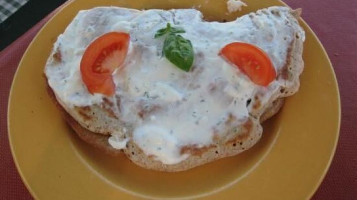 Vollkorn-Eierkuchen mit Garnelen liegt auf einem gelben Teller, garniert mit Tomatenscheiben und frischem Basilikum.