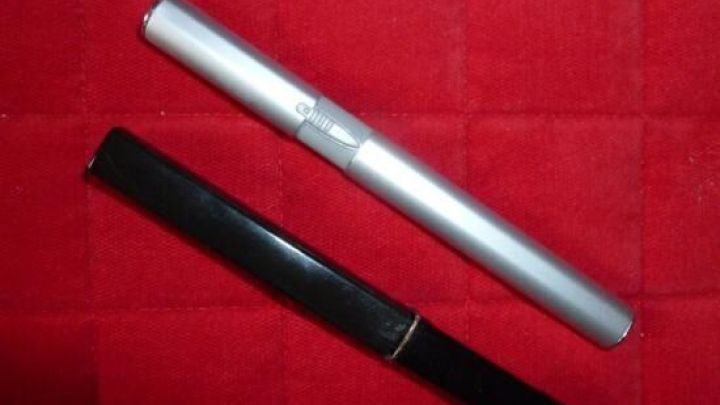 Ein silberner und ein schwarzer Nasenhaarschneider liegen auf einem roten Untergrund, bereit zur Anwendung im Urlaub.