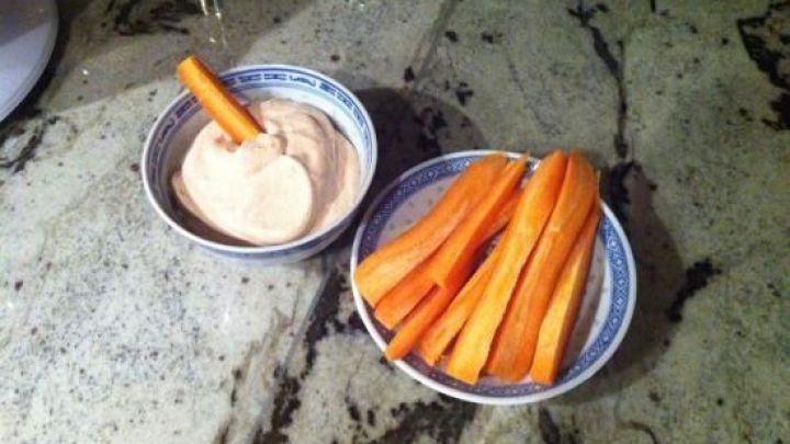 Ein kleiner Dip aus Gem&uuml;se steht in einer Sch&uuml;ssel neben frischen Sticks aus Karotten, ideal zum Snacken.