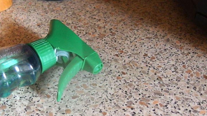 Ein gr&uuml;ner Spr&uuml;hflaschenkopf liegt auf einer Arbeitsplatte, bereit zum Einsatz gegen Ameisen im Haus.