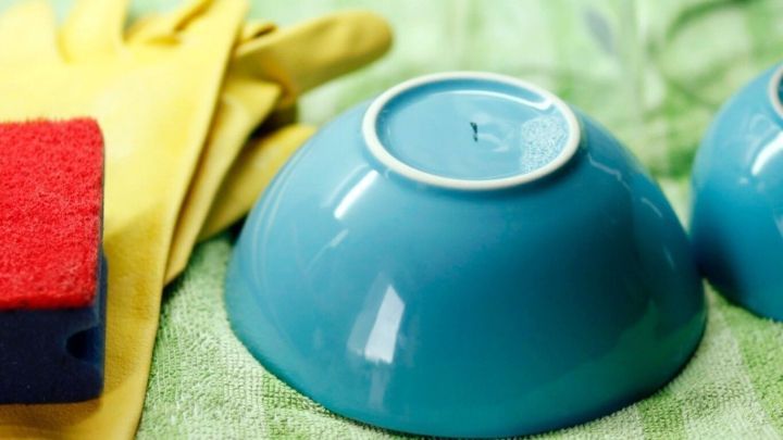 Ein Mikrofaserhandtuch liegt neben einem blauen Geschirr, w&auml;hrend Reinigungsutensilien darauf warten, benutzt zu werden.