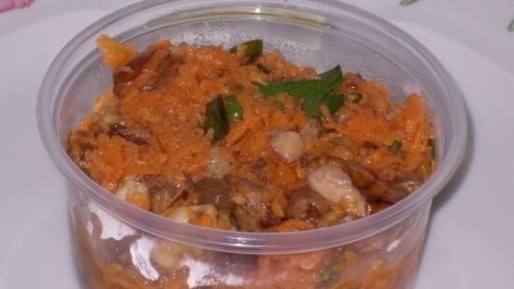 Ein durchsichtiger Beh&auml;lter mit M&ouml;hrensalat steht auf einem blumengemusterten Teller und zeigt frische, geriebene Karotten.