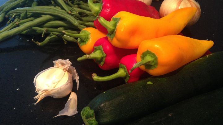 Bunte Paprika, gr&uuml;ne Bohnen und Zucchini liegen auf einer dunklen Oberfl&auml;che und zeigen frisches Gem&uuml;se zum Kauf.