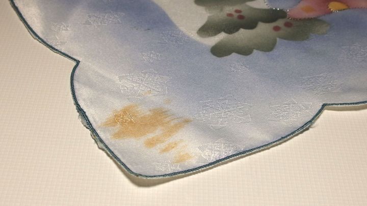 Ein empfindliches Material mit gelben Flecken wird auf einem Tisch betrachtet, um die Notfall-Fleckenentfernung zu demonstrieren.