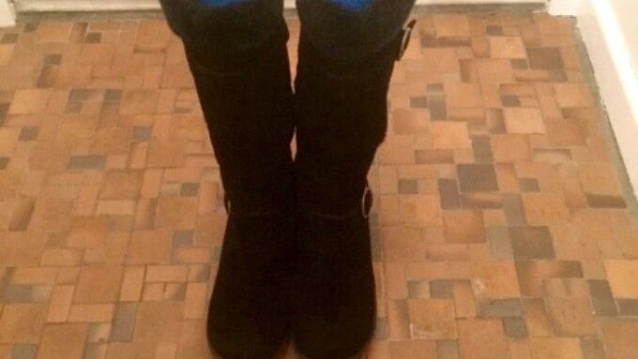 Schwarze Stiefel stehen auf einem Holzboden, stabilisiert durch blaue Poolnudeln im Inneren, die ihnen Form geben.