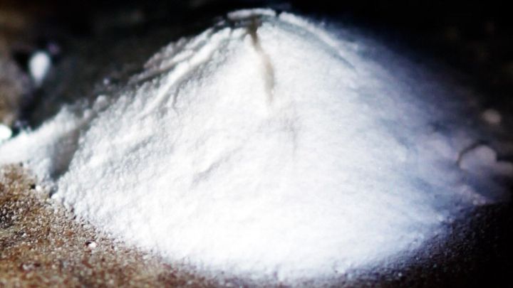 Ein Haufen Natron liegt auf einer Holzoberfl&auml;che, bereit, um Schmutzflecken in wei&szlig;er Jeans zu entfernen.