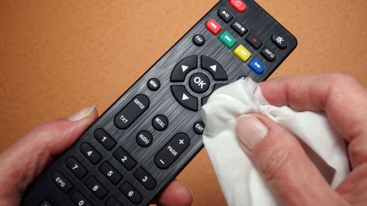 Eine Person reinigt eine Fernbedienung mit einem Tuch, um Hygiene im Hotelzimmer zu gew&auml;hrleisten.
