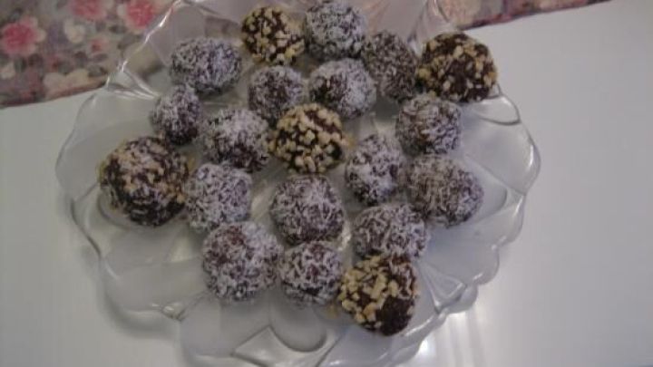 Schwedische Schokokugeln liegen einsatzbereit auf einem eleganten Glas&shy;teller, umgeben von einem floralen Tischtuch.