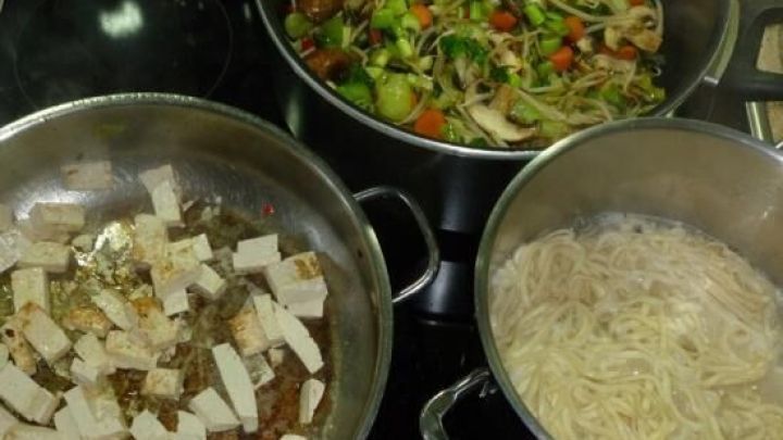 In einer Pfanne br&auml;t Tofu in w&uuml;rziger Marinade, w&auml;hrend daneben knackiger Bokchoikohl und Mie-Nudeln gekocht werden.