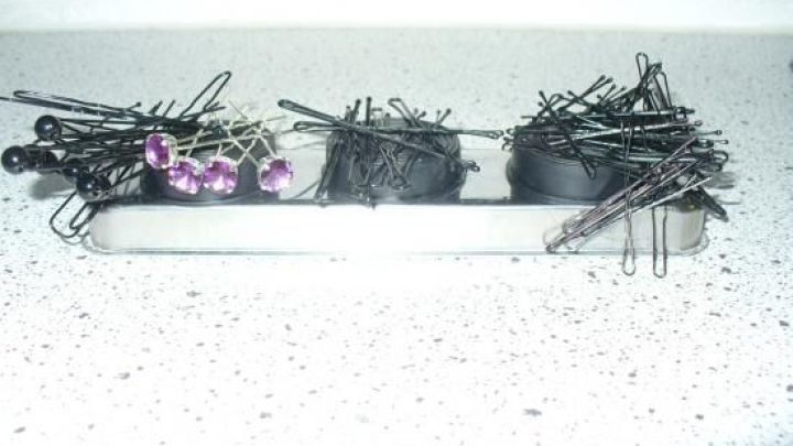 Inmitten von unordentlichen Haarnadeln und Haarklammern auf einer Arbeitsfl&auml;che zeigen sich einige schwarze und pinke Clips.