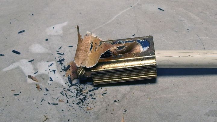 Ein abgebrochener Holzgriff liegt auf einer glatten Oberfl&auml;che, umgeben von Holz- und Graphitsp&auml;nen, die Motten vertreiben.