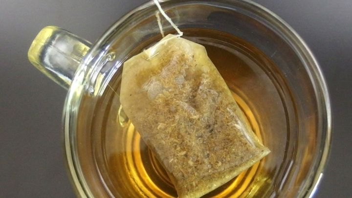 Ein Teebeutel h&auml;ngt &uuml;ber der Tasse mit hei&szlig;em Tee, der zur Linderung von Halsschmerzen dient.