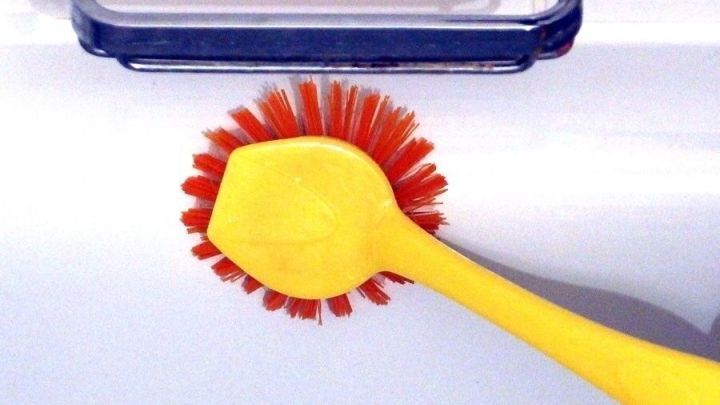 Eine gelbe B&uuml;rste wird auf einer wei&szlig;en Badewanne verwendet, um sie gr&uuml;ndlich zu reinigen und daf&uuml;r zu sorgen, dass sie strahlt.