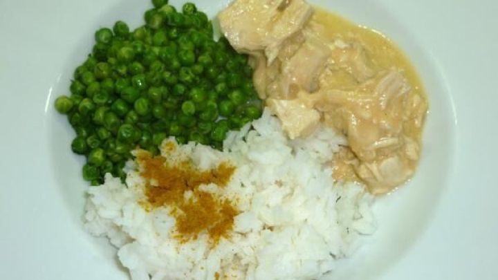 Zarte H&uuml;hnerbrustragoutst&uuml;cke in Zitronenschaumsauce liegen neben gr&uuml;nem Gem&uuml;se und Reis auf dem Teller.