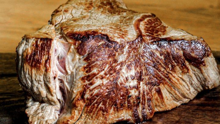 Saftiges, sch&ouml;n braunes Bratenst&uuml;ck liegt auf einem Holzbrett, bereit f&uuml;r die Zubereitung einer k&ouml;stlichen Sauce.