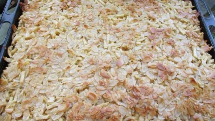 Ein goldbrauner Apfelkuchen liegt auf einem Blech, frisch gebacken und mit knuspriger Kruste, bereit zum Servieren.