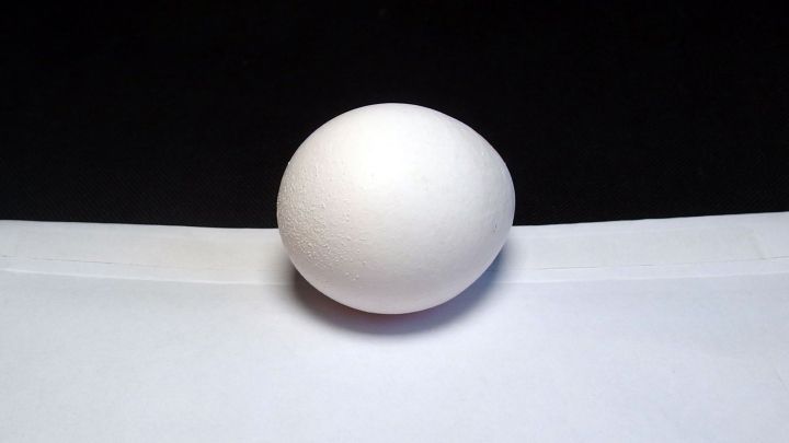 Ein wei&szlig;es Ei balanciert auf einer schmalen Kante in einem dunklen Raum, symbolisiert das Streben, Postgeheimnis zu wahren.