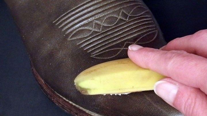 Ein Lederschuh wird mit einer Bananenschale poliert, um ihm Glanz zu verleihen, vor einem neutralen Hintergrund.