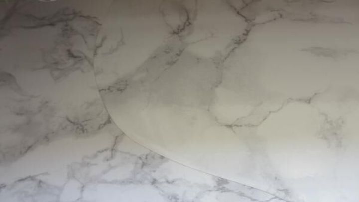 Eine (Klebe)-Folie wird auf einer marmorierten Oberfl&auml;che angebracht, um diese zu gestalten und zu verl&auml;ngern.