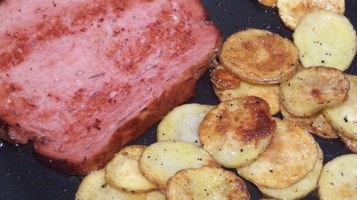 Gegrillte Kartoffelscheiben braten zusammen mit einem St&uuml;ck Fleisch in einer Pfanne, ideal f&uuml;r vorausschauendes Kochen.