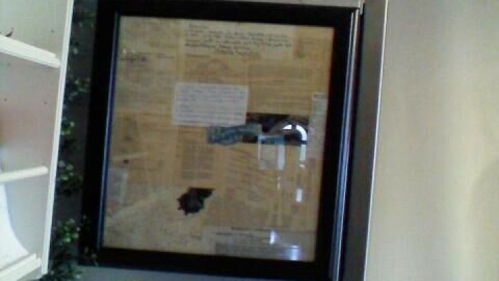 Ein Bilderrahmen wird am K&uuml;hlschrank ohne Bohren befestigt, w&auml;hrend eine Umgebung mit Regalen und einer Teekanne sichtbar ist.