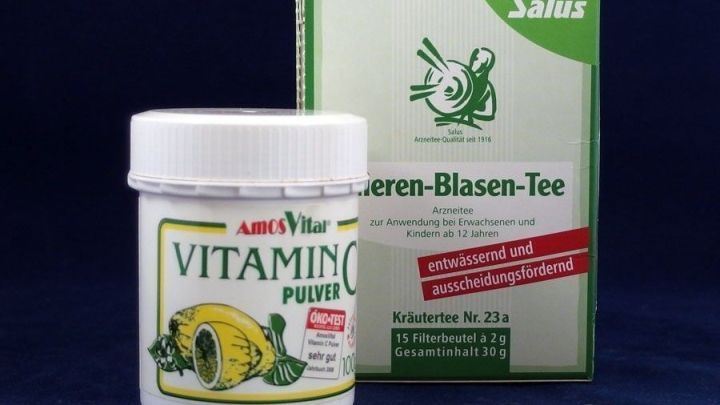 Ein Beh&auml;lter mit Vitamin C-Pulver neben einer Packung f&uuml;r Blasen-Tee zeigt nat&uuml;rliche Heilmittel gegen Blasenentz&uuml;ndung.
