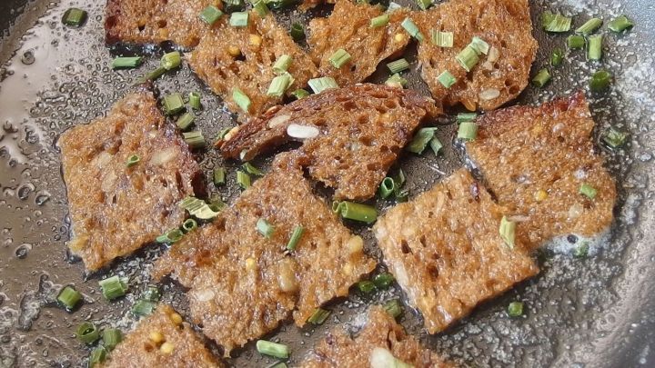 Gebratenes Brot wird goldbraun in einer Pfanne mit frischem Schnittlauch zubereitet, um ein schnelles Mittagessen zu bieten.