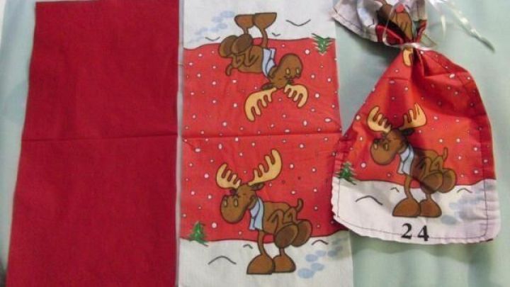 Bunte Servietten liegen zusammen mit einem Adventskalender-S&auml;ckchen aus Servietten auf einem Tisch.