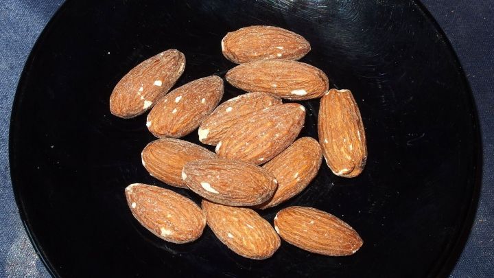 Mandelschalen liegen auf einem schwarzen Teller und zeigen die nat&uuml;rliche Textur der Schalen f&uuml;r ein Gesichtspeeling.