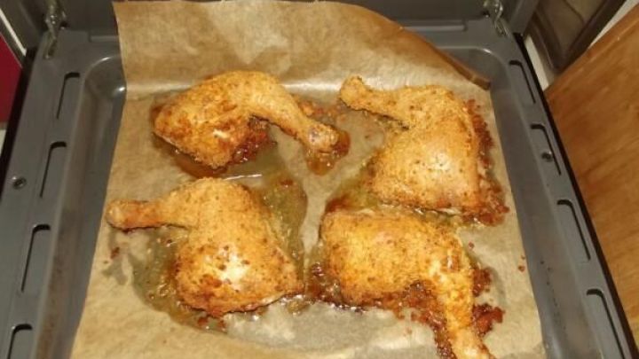 Gebackene H&uuml;hnerbeine liegen goldbraun auf einem Blech mit Backpapier und sind frisch aus dem Ofen genommen.