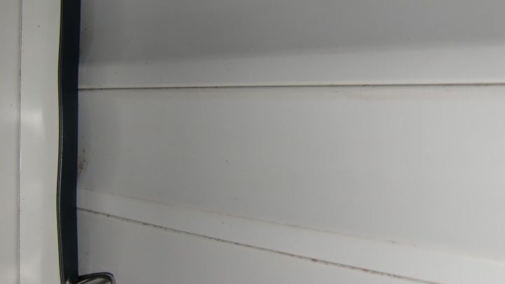 Der klappernde Rollladen bewegt sich unruhig bei Sturm, w&auml;hrend er an einem Fenster in einem schlichten Raum h&auml;ngt.