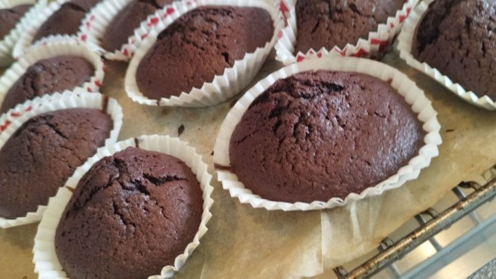Kleine, runde Schokoladenkekse in Herzbechern liegen frisch gebacken auf einem Backblech in einer K&uuml;che.