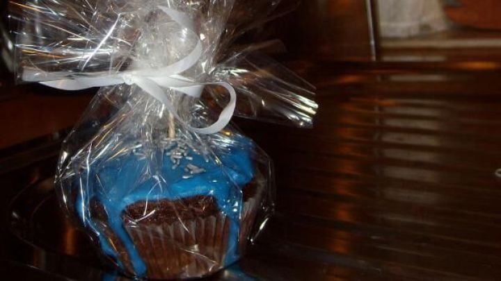 Ein dekorativ verpackter Muffin mit blauer Verzierung und einem Karte, die individuelle Geschenkideen beschreibt.