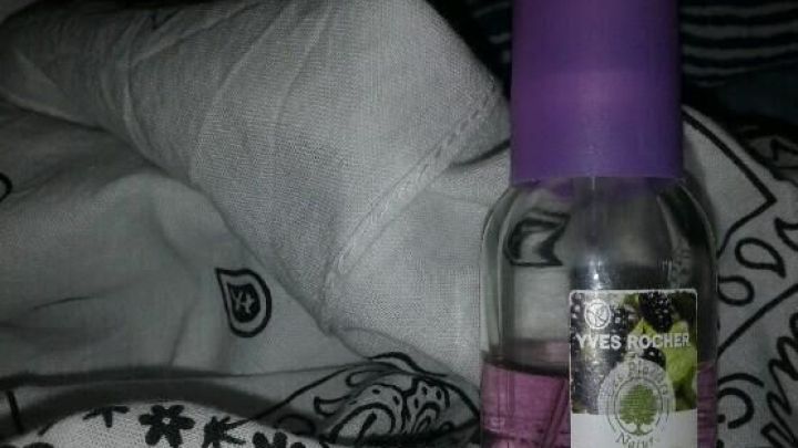 Ein Flakon mit Duft wird auf einem Bett zwischen frischer, gefalteter W&auml;sche platziert, um die W&auml;sche wohlriechend zu halten.