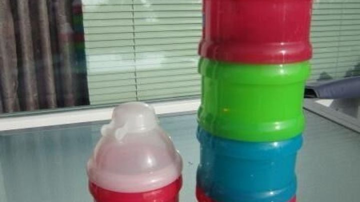 Bunte, stapelbare Gew&uuml;rzbeh&auml;lter stehen auf einem Tisch, sortiert nach Farben, im Hintergrund helle Fensterscheiben.